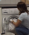 A lady overloading a washing machine