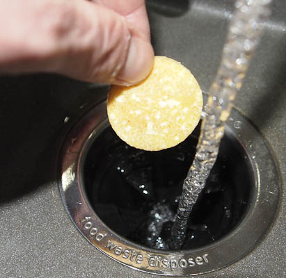 Dropping in an Affresh tablet to clean and freshen the garbage disposal